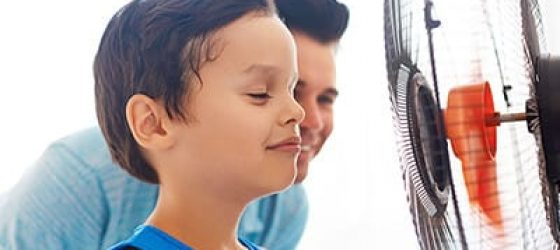 Boy cooling off with fan